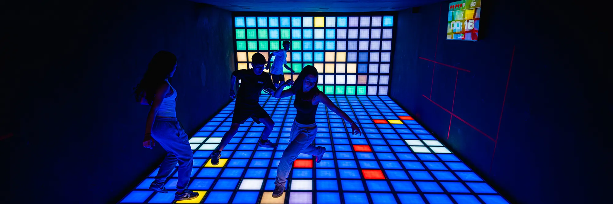 Grupo jogando em uma sala com piso e parede de LED no Arcade Haus